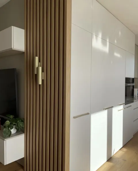 Biela vstavaná skriňa a drevené lamely v obývačke